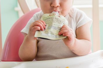 Baby girl eating apple sauce from pouch